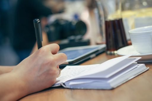 Persoon die aantekeningen maakt in een gezondheidslogboek aan een bureau