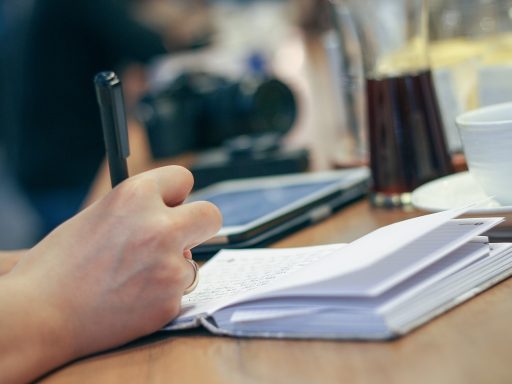Persoon die aantekeningen maakt in een gezondheidslogboek aan een bureau