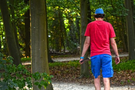 Persoon die alleen wandelt door een groen park op een zomerse dag