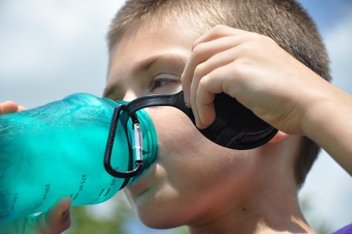 Persoon die water drinkt buiten in de zomerhitte