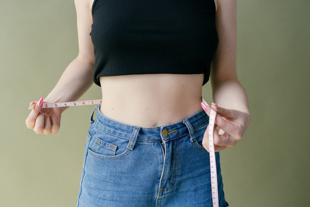 Persoon die de middelomtrek opmeet met een meetlint als aanvulling op BMI