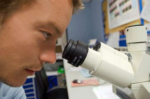 Wetenschapper die door een microscoop kijkt in een medisch laboratorium