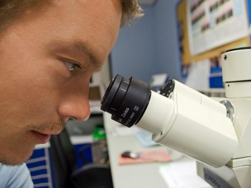 Wetenschapper die door een microscoop kijkt in een medisch laboratorium