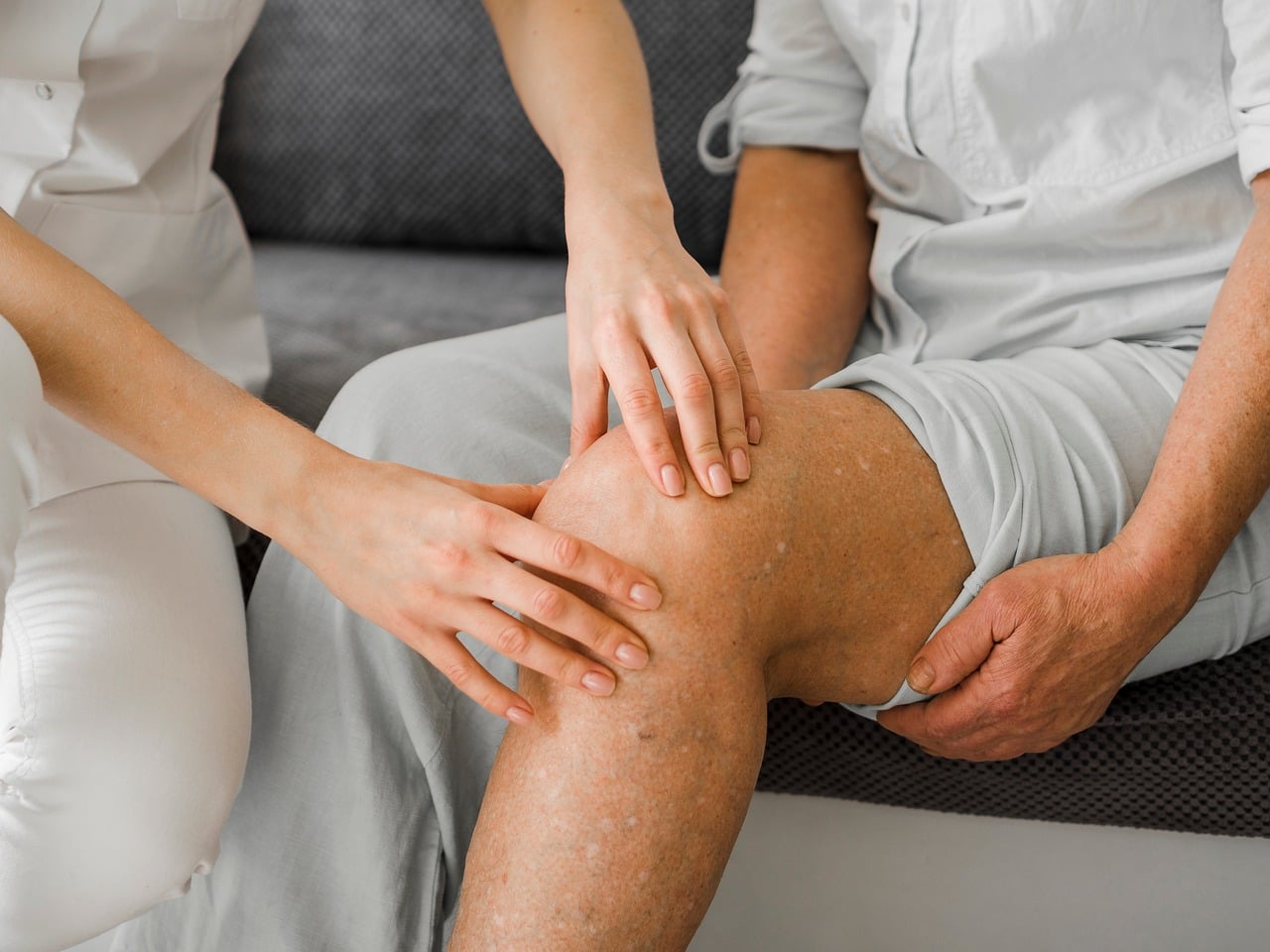 Iemand doet een revalidatieoefening voor de knie onder begeleiding van een fysiotherapeut