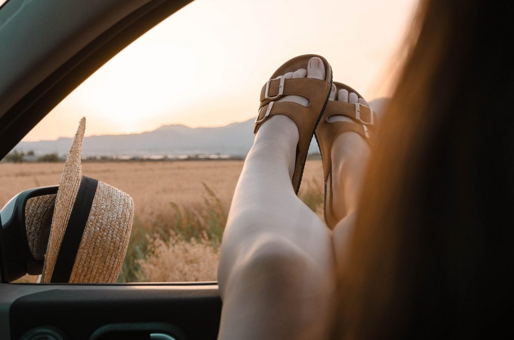 Blote voeten in zomerse sandalen op een warme stenen vloer