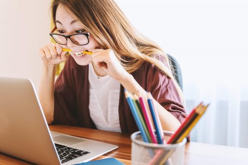 Persoon die gestrest achter een bureau zit met handen tegen het hoofd
