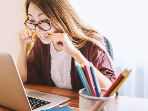 Persoon die gestrest achter een bureau zit met handen tegen het hoofd