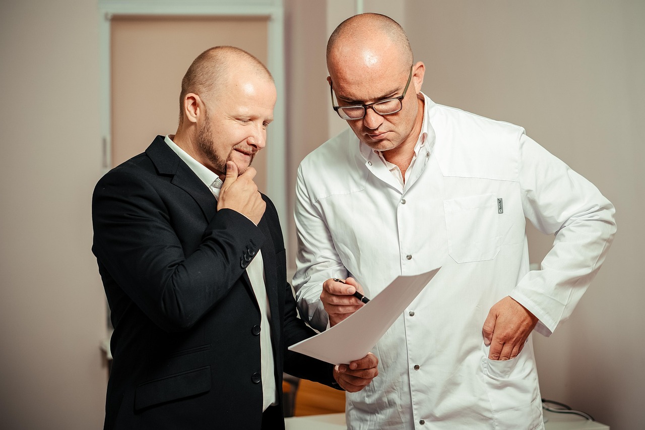 Bedrijfsarts in gesprek met werknemer tijdens consult op kantoor