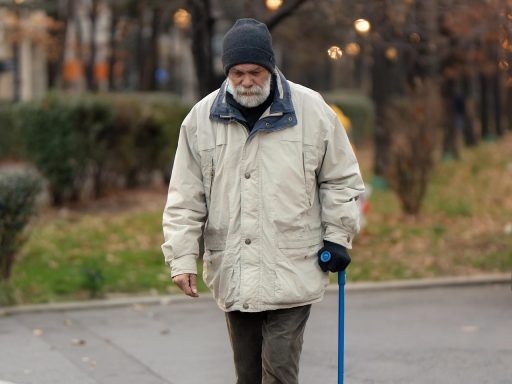 Een oudere man wandelt op een herfstdag door een park met gekleurde bladeren