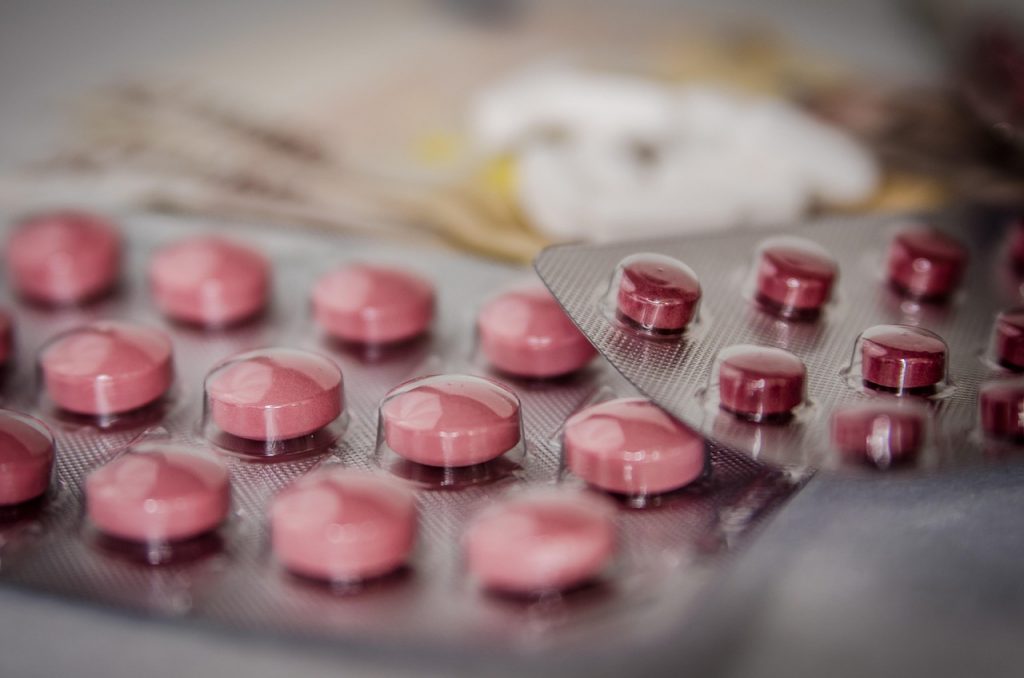 Medicijnpotjes en pillen naast een reistas klaar voor vertrek naar het buitenland