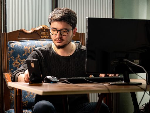 Persoon die op een laptop een online therapiesessie volgt aan een bureau thuis