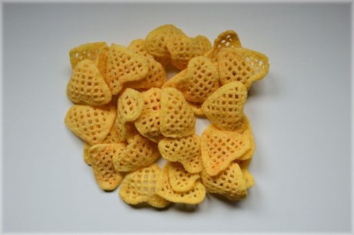Een jong kind dat crackers eet aan een keukentafel