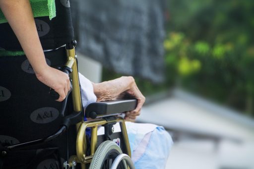 Een verpleegkundige helpt een oudere patiënt in een zorginstelling
