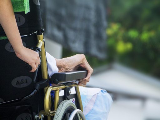 Een verpleegkundige helpt een oudere patiënt in een zorginstelling