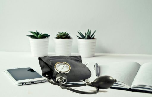 Persoon meet bloeddruk thuis met een bovenarmapparaat aan de keukentafel