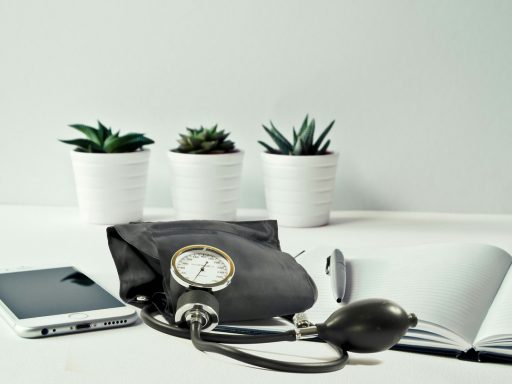 Persoon meet bloeddruk thuis met een bovenarmapparaat aan de keukentafel