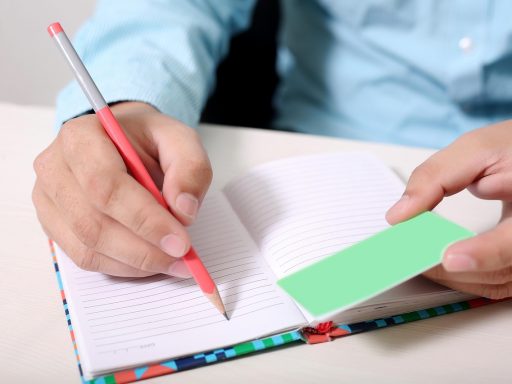 Persoon schrijft in een notitieboekje aan een tafel