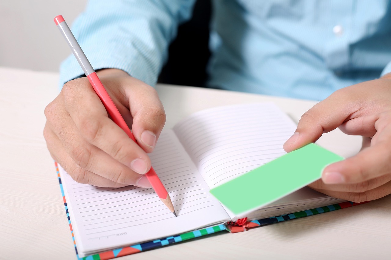 Persoon schrijft in een notitieboekje aan een tafel